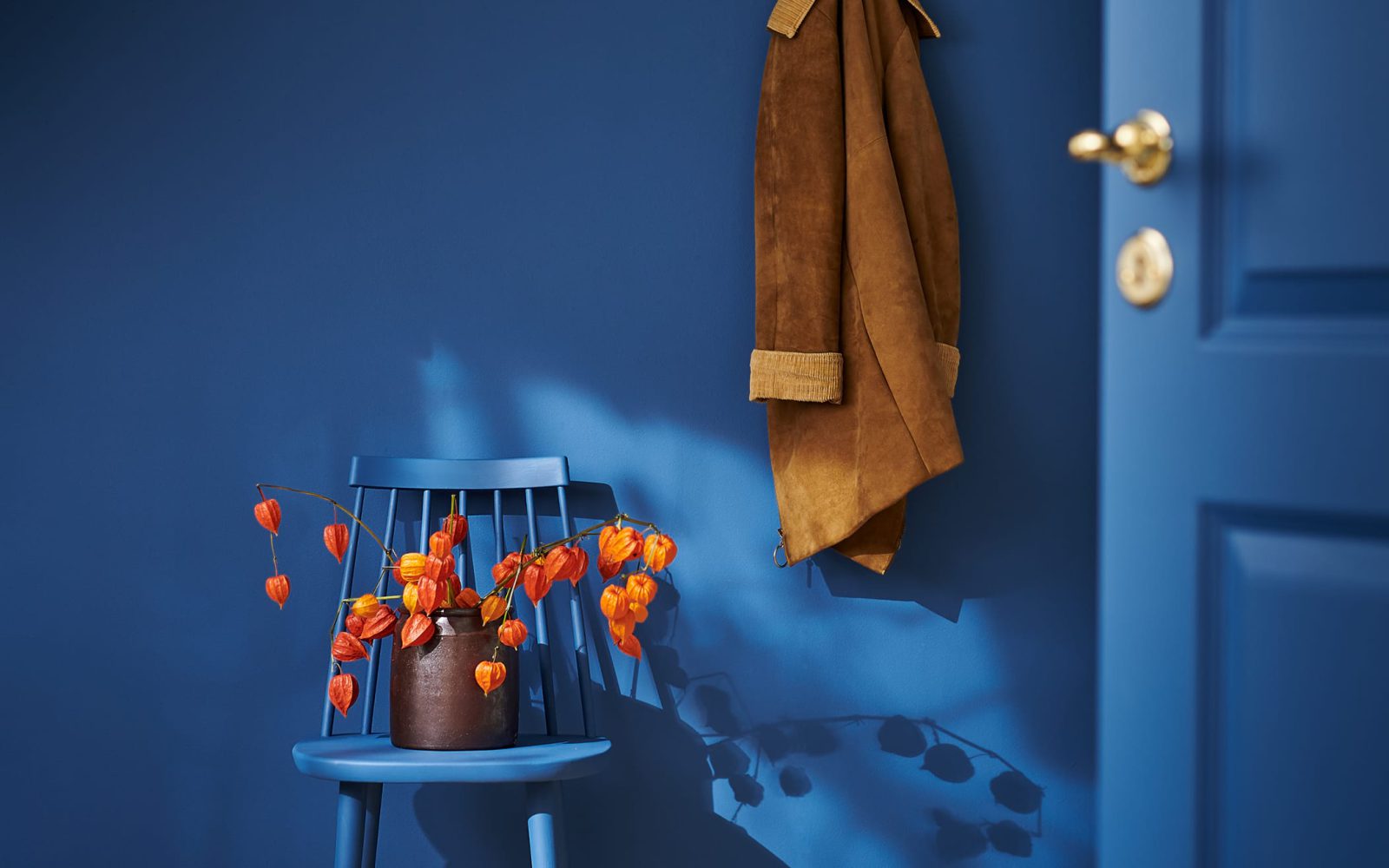 Rummet, dörren och stolen är helt målat i blått och på stolen står en orange växt