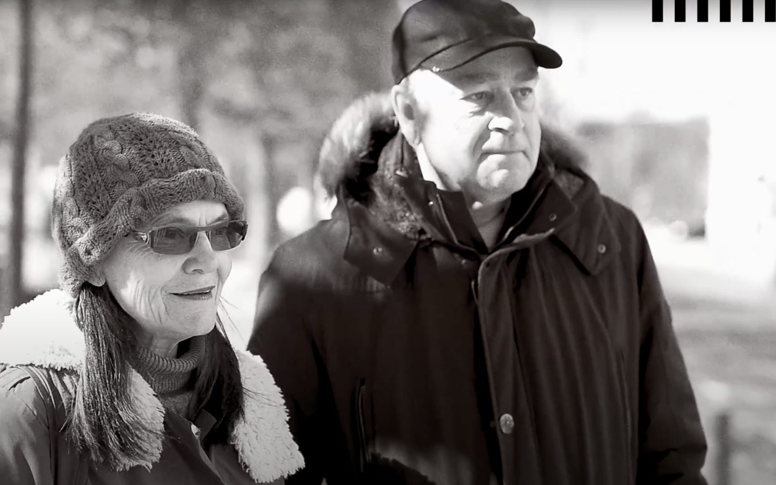 Äldre par i vinterjackor från Landskrona tittar åt sidan