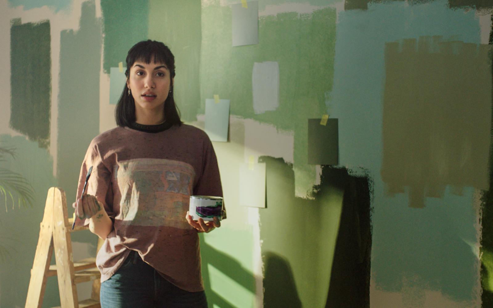 Kvinna provmålar olika nyanser av grönt på väggen