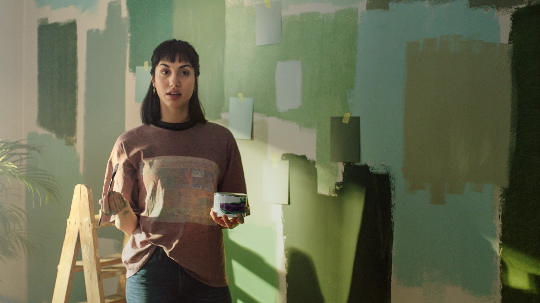 Kvinna provmålar olika nyanser av grönt på väggen