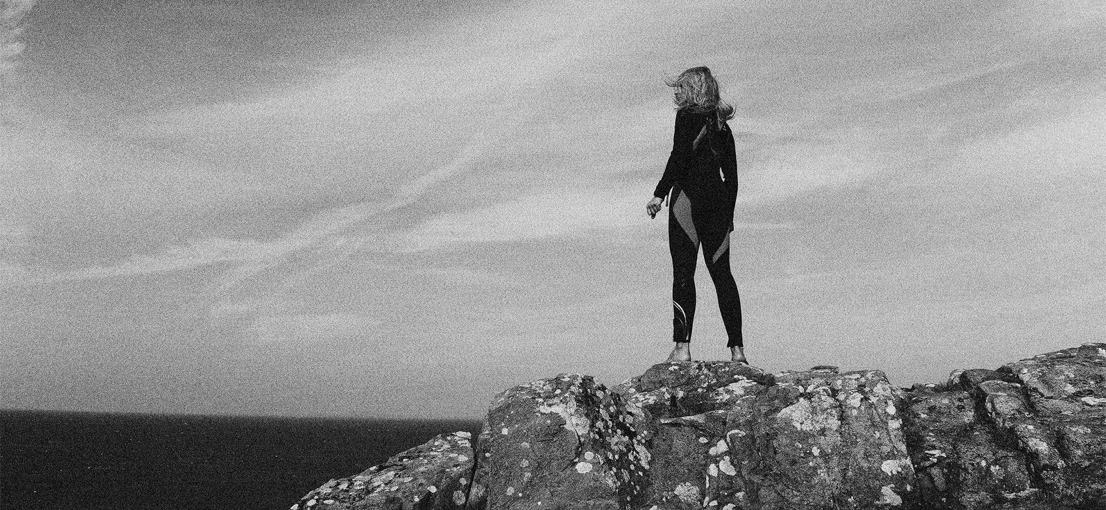 Kvinna står på en klippa och tittar ut över havet